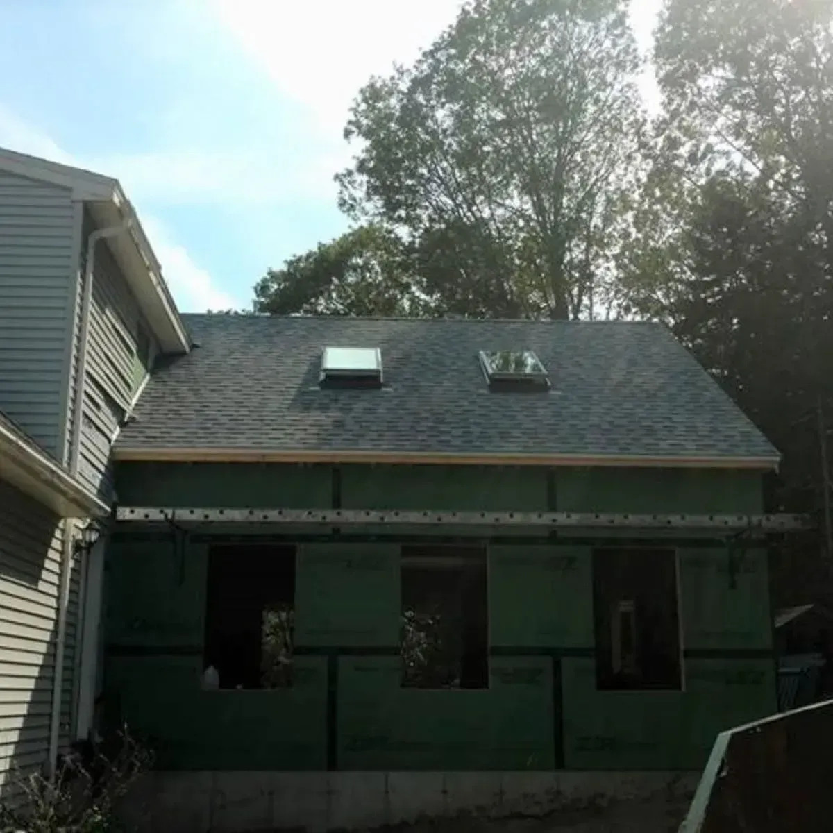 A green house addition is under construction with three skylights visible on the roof.